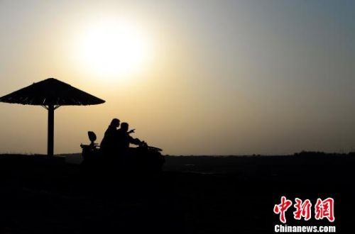 落日下，游客驾驶沙丁车在沙漠中飞奔。　涂欢 摄